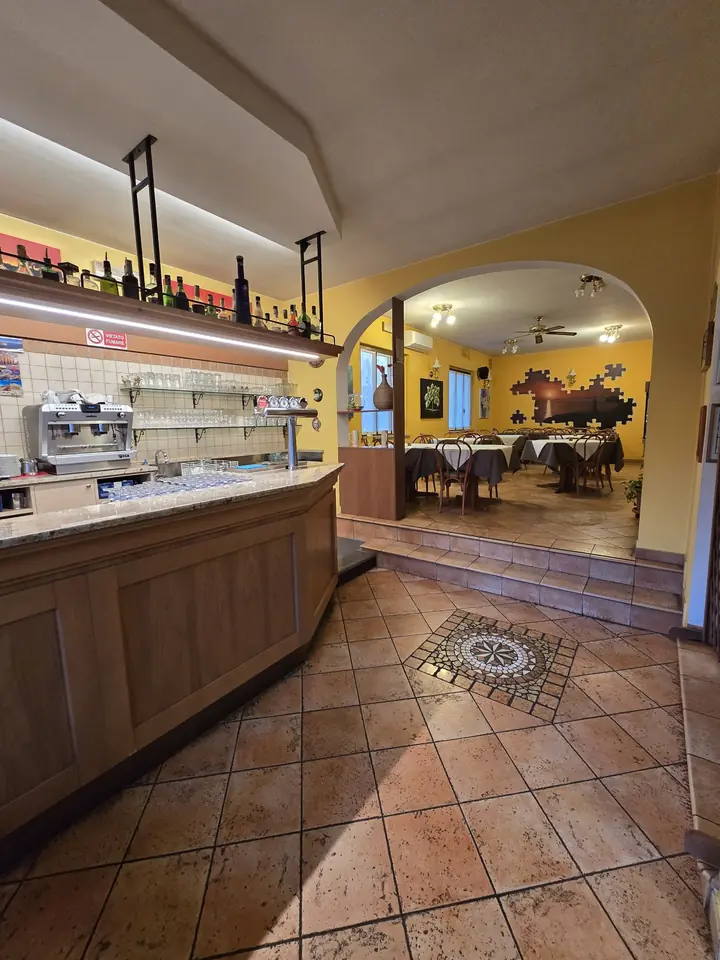 Il bancone del bar all'ingresso e l'arco che porta alla sala